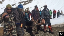 Nepalese army, rescue team members carry avalanche victims to safety at Thorong La pass area in Nepal, Oct. 17, 2014.