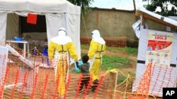 FILE - Health workers walk with a boy suspected of having been infected with the Ebola virus, at an Ebola treatment center in Beni, near Congo's border with Uganda, Sept. 9, 2018.
