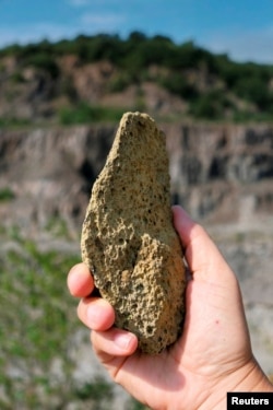 FILE - A person holds a heavily weathered artefact, a stone flake at the Korolevo I site in western Ukraine, Korolevo, Ukraine, August 23, 2023. (Roman Garba/Handout via REUTERS)