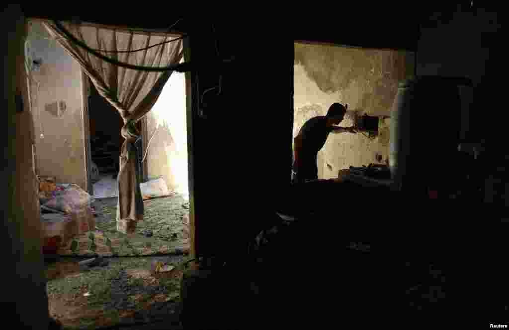 A Palestinian man inspects a house which police said was damaged in Israeli shelling that killed two boys and a man from the Nutaiz family, in Gaza City, July 18, 2014.