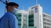 FILE - A police officer stands guard outside the Apple Daily headquarters in Hong Kong after arresting the chief editor and four other senior executives of the newspaper, In this Thursday, June 17, 2021.