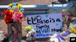 Unas flores y una imagen de la Virgen de Guadalupe adornan un monumento conmemorativo improvisado en honor de las víctimas de un tiroteo en un centro comercial en El Paso, Texas, el domingo 4 de agosto de 2019. El letrero dice: "El Paso es una familia. Permanecemos unidos".