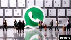 En esta ilustración, tomada el 12 de abril de 2020, un logotipo de Whatsapp impreso en 3D aparece entre pequeñas figuras de personas de juguete frente a un teclado.