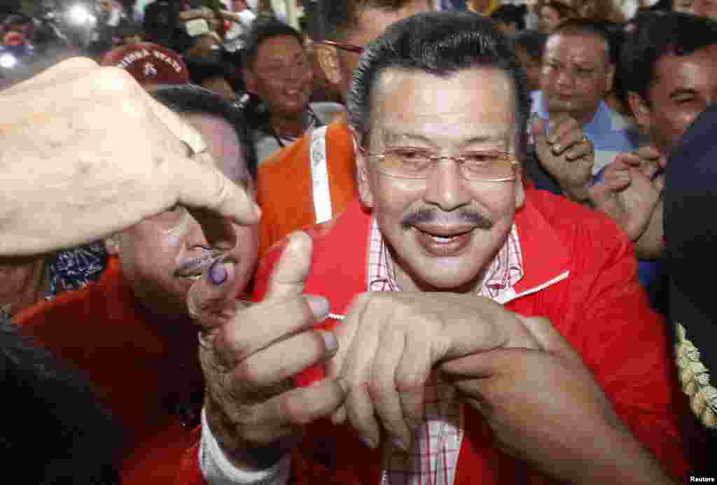 A supporter greets former Philippine President Joseph Estrada after he cast his vote inside a precinct poll at a school in Manila, May 13, 2013.