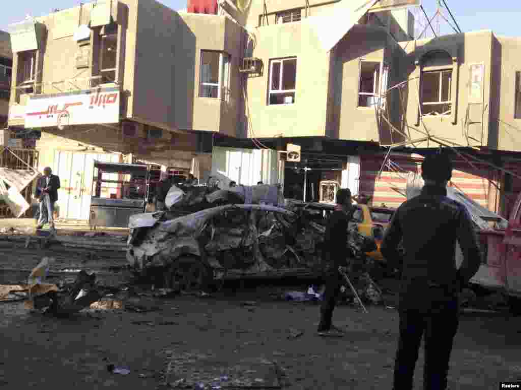 People look at the site of a car bomb attack in Baghdad, Jan. 20, 2014.