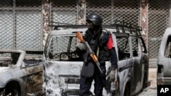 Un officier de police monte la garde à côté des voitures brûlées près du Splendid Hotel à Ouagadougou, Burkina Faso, 17 janvier 2016