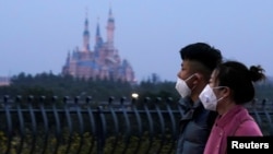 戴著口罩的上海市民從春節期間關閉的迪斯尼樂園旁走過。 （2020年1月24日）