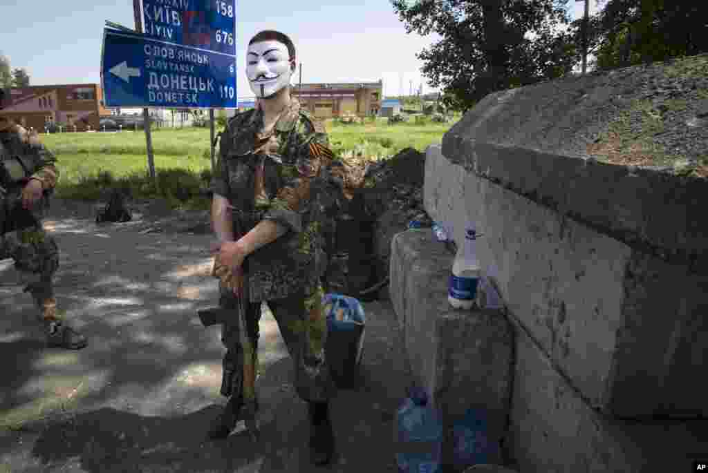Seorang militan pro-Rusia yang bertopeng berdiri di belakang barikade di sebuah pos pemeriksaan yang menghalangi jalan layang di luar kota Kharkiv, Ukraina timur (17/5). (AP/Alexander Zemlianichenko)