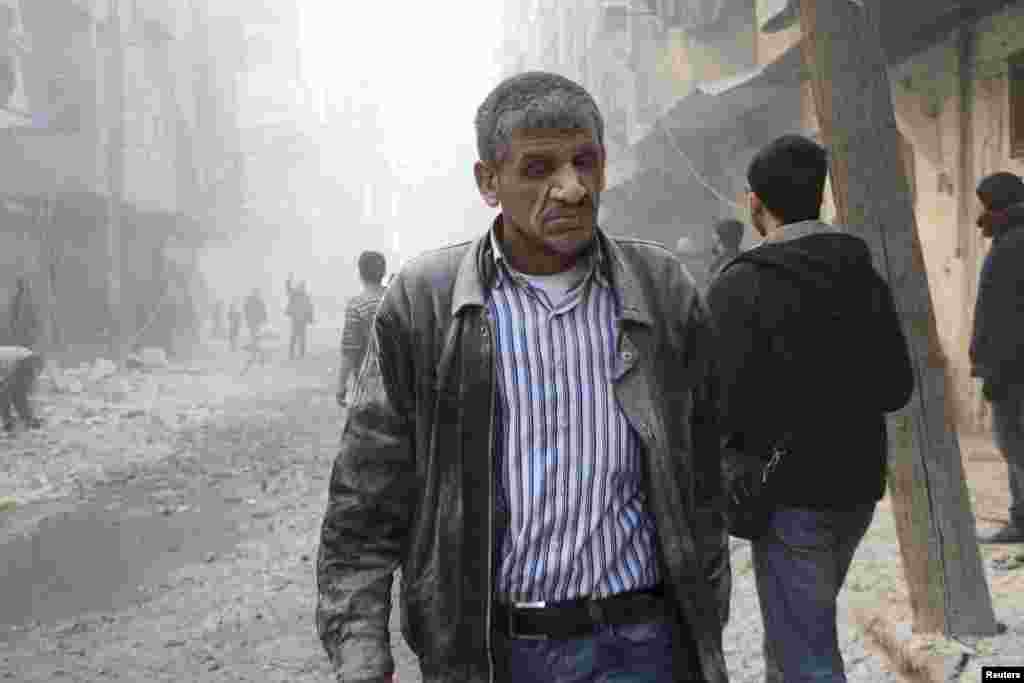 A man walks at a site hit by what activists said was a barrel bomb dropped by forces loyal to President Bashar Assad in the al-Shaar district, Aleppo, Feb. 9, 2014. 
