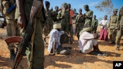 FILE - Alleged members of al-Shabab are blindfolded and guarded at a former police station by soldiers of the Somali National Army (SNA) in Kismayo, southern Somalia, Oct. 3, 2012.