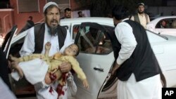 Un homme transporte un petit garçon blessé, après un attentat à la voiture piégée devant un stade de Lashkar Gah, capitale de la province du Helmand, le 23 mars 2018.