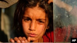 A Syrian girl who is newly displaced by the Turkish military operation in northeastern Syria, weeps as she sits in a bus upon her arrival at the Bardarash camp, north of Mosul, Iraq, Wednesday, Oct. 16, 2019. 