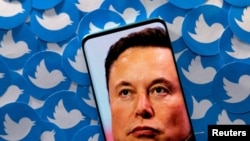 ARCHIVO - Se ve una imagen de Elon Musk en un teléfono colocado en logotipos impresos de Twitter en esta ilustración tomada el 28 de abril de 2022. 