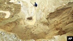 A worker waters the site of a rare earth metals mine at Nancheng county, Jiangxi province, China 29 Dec 2010
