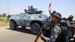 Des policiers fédéraux irakiens patrouillent à Abou Ghraib, dans la banlieue de Bagdad, en Irak, 28 juin 2014 .. AP, Bagdad