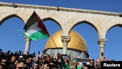 Fieles ondean la bandera palestina durante protestas tras las oraciones del viernes en el complejo conocido para los musulmanes como el Noble Santuario y para los judíos como Templo del Monte en la ciudad vieja de Jerusalén, el viernes, 8 de diciembre de 2017.