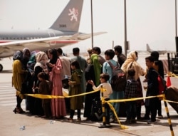 In this photo provided by the U.S. Marine Corps, civilians prepare to board a plane during an evacuation at Hamid Karzai International Airport, Kabul, Afghanistan, Wednesday, Aug. 18, 2021.