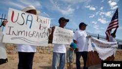 ARCHIVO - Residentes de la frontera mexicana y miembros de la Red Fronteriza de Derechos Humanos (BNHR) sostienen carteles y pancartas durante una protesta contra la militarización fronteriza y la deportación de niños, frente a un centro de detención en El Paso, Texas, el 24 de agosto de 2017.