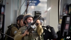 Seorang tentara Israel menembakkan gas airmata dalam bentrokan dengan demonstran Palestina dekat kota Ramallah, Tepi Barat, Senin (12/10)