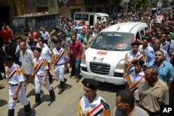 Egyptian policemen march with a vehicle carrying the body of their comrade, killed Monday in Cairo outside Republican Guard headquarters in an incident that left 51 people dead, at his funeral in Alexandria, July 9, 2013.