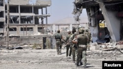 Soldiers loyal to Syria's President Bashar al-Assad are seen at an industrial area in the al-Kaboun neighborhood in Damascus after taking control of it from the Free Syrian Army, July 6, 2013. (Photo distributed by Syria's national news agency SANA)