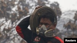 An Indonesian firefighter carries a fire hose as he walks after fighting burning palm oil trees at a palm oil plantation at Jebus village in Muaro Jambi, on the Indonesian island of Sumatra, September 16, 2015.