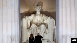 El presidente electo Donald Trump y su esposa, Melania Trump, saludan el monumento del Lincoln Memorial, al llegar la noche anterior a su posesión como presidente de EE.UU., al "Make America Great Again Welcome Concert".