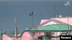 A still image taken from a video posted to a social media website by the Islamic State-affiliated Amaq News Agency on June 12, 2017, shows a black flag perched on a building in Marawi City, Philippines.