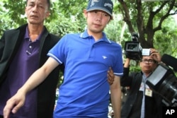 FILE - Vorayuth "Boss" Yoovidhya, center, whose grandfather co-founded energy drink company Red Bull, is escorted by police in Bangkok, Thailand, Sept. 3, 2012.