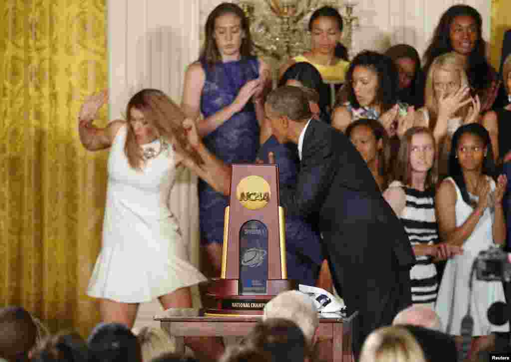 U.S. President Barack Obama hugs UConn women's basketball coach Geno Auriemma as team star Stefanie Dolson (L) falls off the stage in the background during a ceremony honoring the NCAA basketball champion University of Connecticut Huskies men's and women's basketball teams in the East Room of the White House in Washington, June 9, 2014. Dolson was unhurt in the fall.