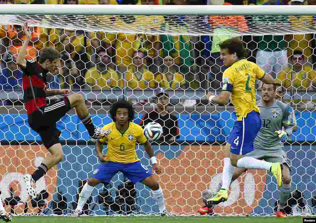 Pemain Jerman, Thomas Mueller (kiri) saat mencetak gol pertama Jerman ke gawang Julio Cesar, Brazil.