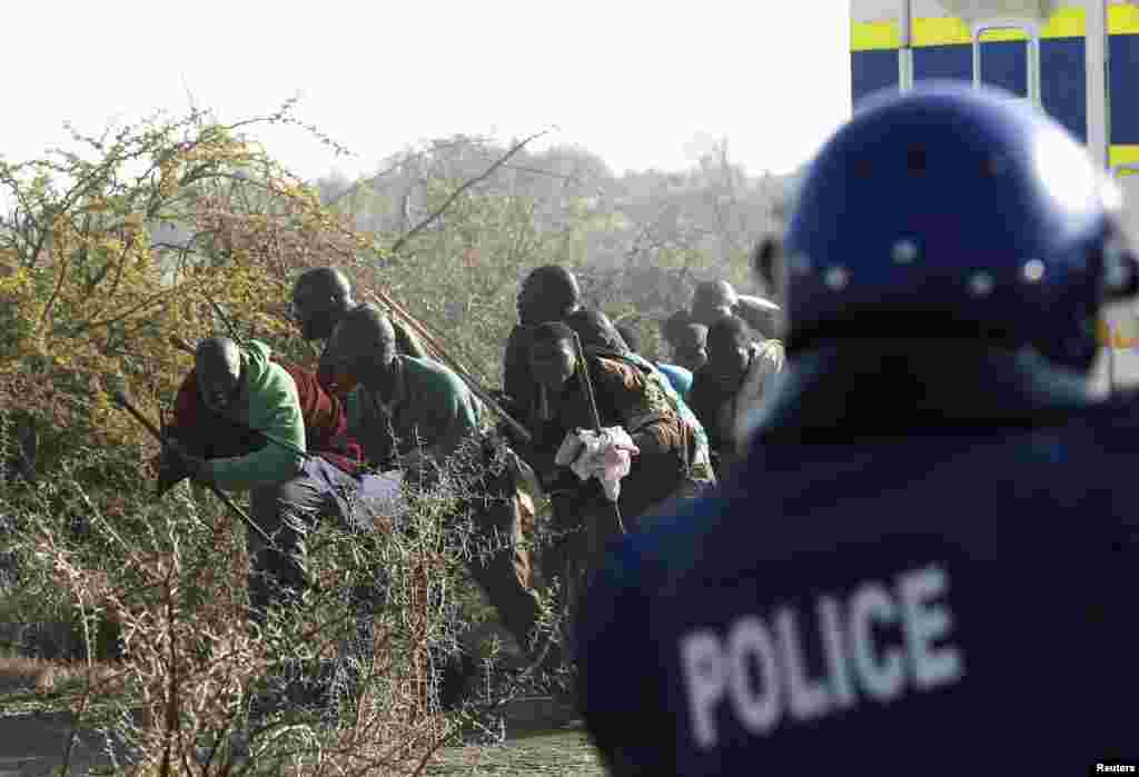 A policeman fires at protesting miners outside a South African mine in Rustenburg, August 16, 2012.