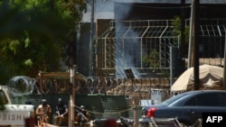 Des agents de sécurité se mettent à l'abri lors d'une prise d'otage, à Ouagadougou, le 2 mars 2018.