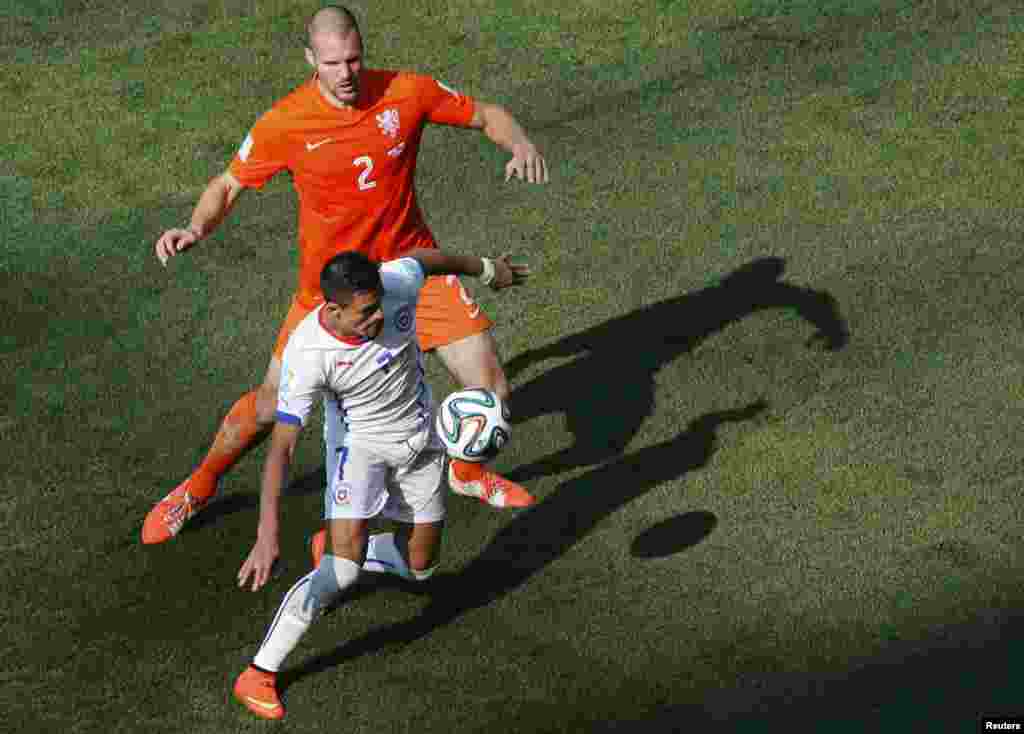 Pemain Chile Alexis Sanchez memperebutkan bola dengan Ron Vlaar dari Belanda dalam pertandingan di arena Corinthians di Sao Paulo, 23 Juni 2014.