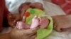 In this Nov. 5, 2015 photo, a couple from Britain whose baby was born on Oct. 17 by a surrogate pose their baby for a photo in Anand, India. For 15 years the couple were unable to get pregnant and turned to Dr Nayna Patel's clinic after seeing her on a TV program. (AP Photo/Allison Joyce)