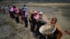 FILE - Rohingya refugee women carry baskets of dried out mud from the riverbed to help raise the ground level of their camp in preparation for monsoon season, in Shamlapur refugee camp, in Cox's Bazaar, Bangladesh, March 24, 2018.