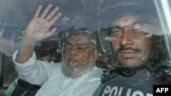 Sekjen Jamaat-e-Islami, Ali Ahsan Mohammad Mujahid (kiri) melambaikan tangannya dari mobil polisi saat dibawa kembali ke penjara seusai menjalani sidang di Pengadilan Dhaka, Bangladesh (17/7).