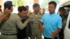 Chay Sarith, second left, and Mao Hoeun, second right in light blue shirt, suspected attackers who are accused of beating two opposition lawmakers along with another man, are escorted by police officers at Phnom Penh Municipal Court in Phnom Penh, Cambodia, Wednesday, Nov. 4, 2015. Three suspects of the assault outside of the National Assembly last week made confessions on Tuesday, according to a government statement released late Tuesday. (AP Photo/Heng Sinith)