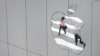 FILE - A woman is reflected in a Apple store logo in San Francisco, California, Aug. 21, 2017. 