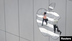 FILE - A woman is reflected in a Apple store logo in San Francisco, California, Aug. 21, 2017. 