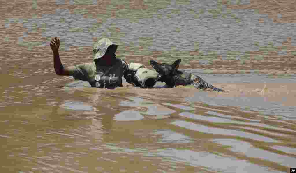 Un exercice de simulation montrant un chein dressé appréhendant un "braconnier de rhino", au centre, après la descente d'un hélicoptère dans l'eau, dans une académie dirigée par le Groupe Paramount, près de Rustenburg, Afrique du Sud, 26 novembre 2014.