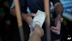 Un cliente paga en un abasto en el mercado periférico de Valencia el 1 de febrero de 2024. El BCV publicó que la inflación de mayo fue de 1,5 %.
