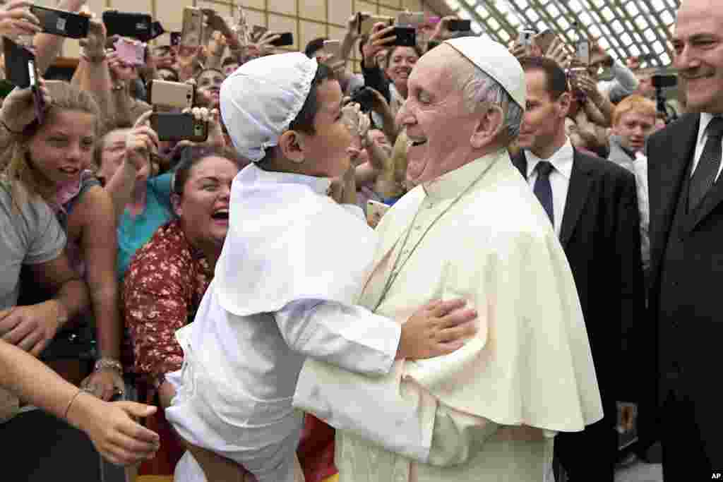 សមេ្តច​ប៉ាប​ Francis លើក​កុមារ​ម្នាក់​ដែល​ស្លៀក​ពាក់​ដូច​សម្តេច​នៅ​ក្នុង​កិច្ច​ស្វាគមន៍​សាសនិក​ជន​នៅ​សាល​ Paul VI បុរី​វ៉ាទីកង់។ &nbsp;