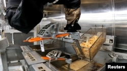 Robot Flippy 2 mengeluarkan kentang goreng di laboratorium pabrikan Miso Robotics Inc di Pasadena, California, AS 27 September 2022. (Foto: Sandra Stojanovic/REUTERS TV via REUTERS)
