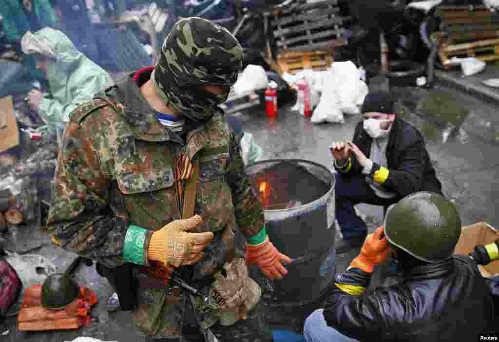 Pro-Russian men warm themselves near a fire at a barricade near the police headquarters in Slovyansk, April 13, 2014. 