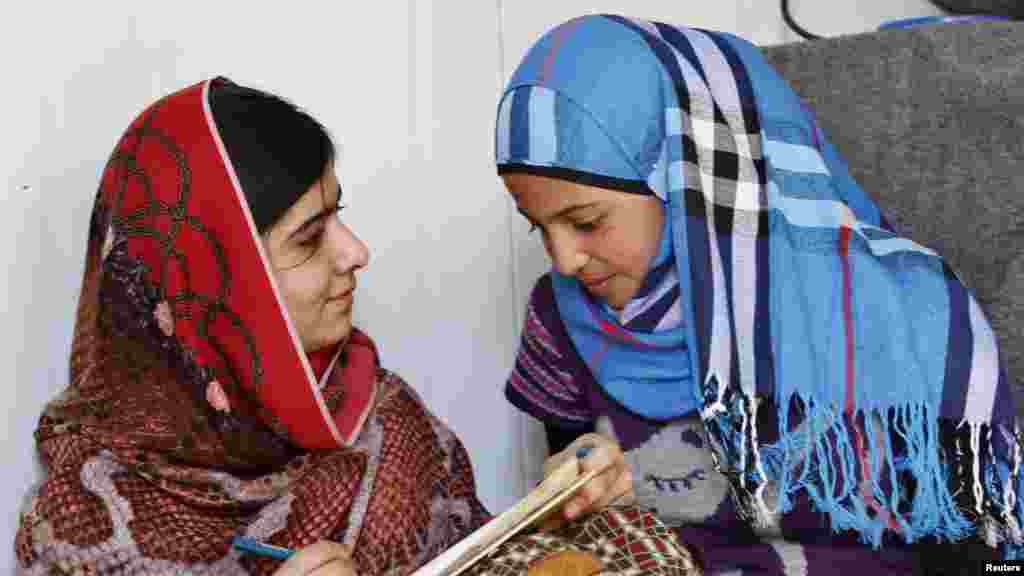 Malala Yousafzai, à gauche échange avec à une réfugiée syrienne âgée de 16 ans, Mazoon Rakan, de l’expérience de Mazoon comme réfugiée dans ce camp de Zaatri, dans la ville de Mafrag, en Jordanie près de la frontière avec la Syrie, le 18 février 2014. REUTERS/Muhammad Hamed
