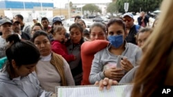 En esta foto del 23 de octubre de 2018, mujeres en Tijuana, México, observan mientras funcionarios llaman números y nombres para cruzar la frontera y solicitar asilo en Estados Unidos.
