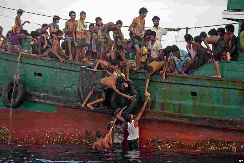 Para migran Rohingya membagikan pasokan makanan yang dijatuhkan oleh helikopter militer Thailand di atas kapal yang terapung di perairan Thailand, lepas pantai pulau Koh Lipe di Laut Andaman (14/5). (AFP/Christophe Archambault)