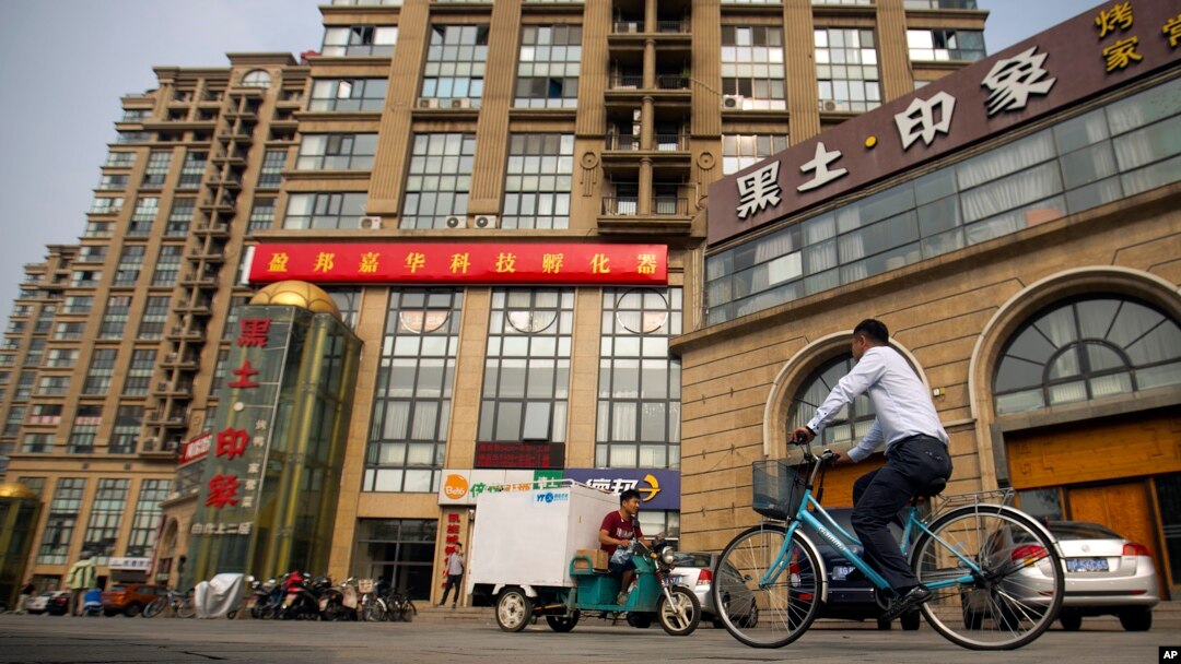 FILE - A delivery cart and cyclist ride past a building housing the Fengrui law firm in Beijing. Several lawyers from the firm have been targeted by authorities.