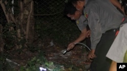 Polisi Burma memeriksa sebuah bom kecil yang meledak di pinggiran ibukota Rangoon (13/10). 